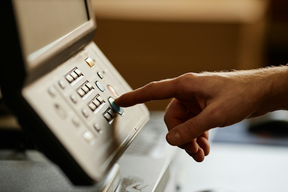 Hand pressing buttons on printer