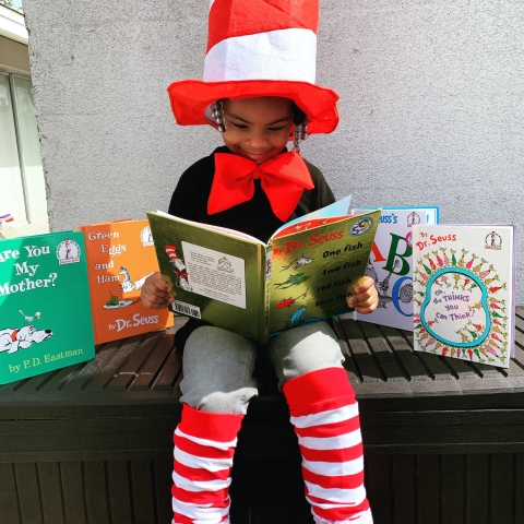 Young girl reading in Cat in the Hat costume. 