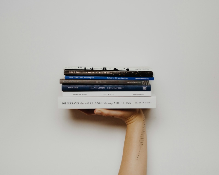 Hand holding up stack of books